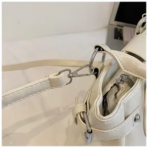 White PU leather shoulder bag detail shot showing metal hardware, zippers and straps clearly.
