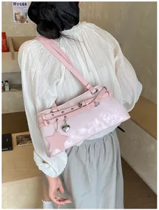 Pink shoulder bag detail showing star heart charms, stylish leather texture and buckle strap design.