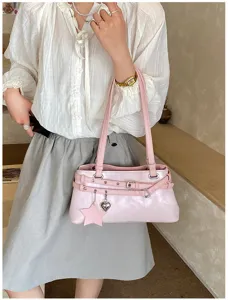 Pink shoulder bag detail view with buckle straps and cute star heart charms for women