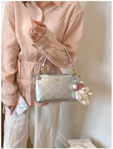 Silver quilted underarm shoulder bag detail shot with cute bear keychain and metallic strap.