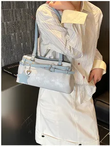 Light blue leather shoulder bag with decorative buckle and star charm detail close up view.