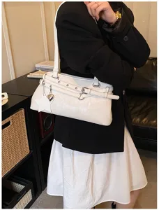 Stylish white underarm shoulder bag with metal eyelet strap details and cute charms.