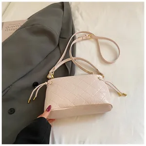 Close-up detail of light pink quilted shoulder bag with chic drawstring and metal hardware.