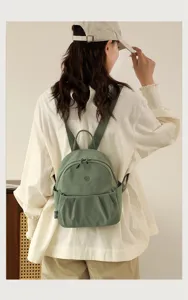 Detailed view of casual nylon mini backpack in green, featuring front pocket and shoulder straps.