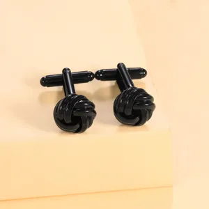 Gros plan détaillé des boutons de manchette élégants en métal noir avec un design torsadé.