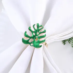 Close-up shot of a decorative green leaf metal napkin ring placed on white cloth.