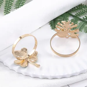 Detailed view of shiny gold metal clover and plant leaf napkin rings for elegant table decor.