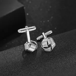 Boutons de manchette en métal argenté, design creux détaillé pour chemises formelles.