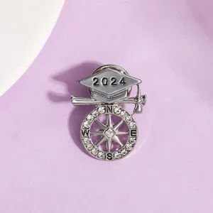 Detailaufnahme der Abschlussbroche 2024 mit Strasskompass und Doktorhut-Design.