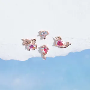 Vista detallada de pendientes de oro rosa con encantadores dijes de unicornio y ballena.