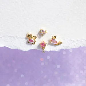 Detalle exquisito de pendientes de botón de oro con circonita colorida de unicornio y delfín.
