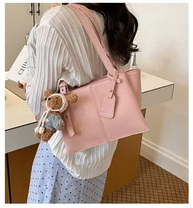 Stylish pink leather tote bag for women, large capacity shoulder bag with cute bear pendant.