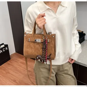 Detail view of the elegant brown shoulder bag featuring metal lock and cute charm pendant.