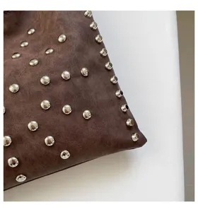 Detailed view of trendy retro brown shoulder tote bag featuring metallic silver round studs.