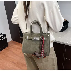 Detail view of stylish olive green shoulder bag with cute dachshund pendant and metal clasp.