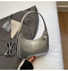 Detailed view of shiny silver patent leather hobo shoulder bag with sleek curved design.