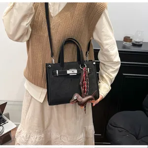 Black shoulder handbag with metal lock and cute dog pendant, stylish daily commuter crossbody bag.