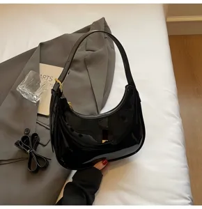 Black patent leather underarm bag detail, crescent shape chic baguette handbag style.