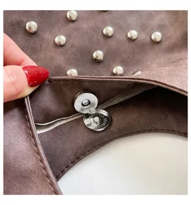 Brown studded shoulder bag detail view, metal magnetic snap and rivet interior display.
