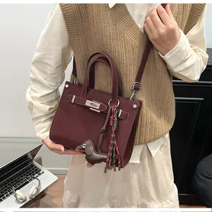 Chic burgundy women shoulder bag, trendy crossbody tote bag with cute dog pendant and strap decor.