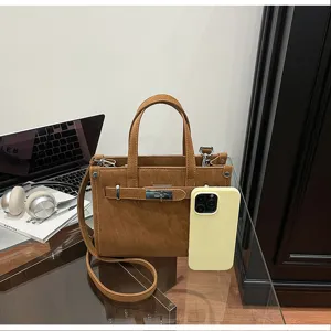 Detailed view of the brown leather shoulder bag featuring metal lock and elegant modern setting.