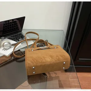 Stylish brown suede crossbody bag with metal turn-lock and top handle for women daily commute.
