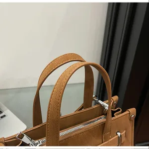 Close-up detail of stylish brown leather handbag handle and metal hardware. Premium design.