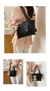 Stylish black leather tote bag with cute bear pendant, perfect for daily commuting and women.