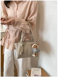 Detailed view of the chic leather tote bag with cute knit bear pendant for women.