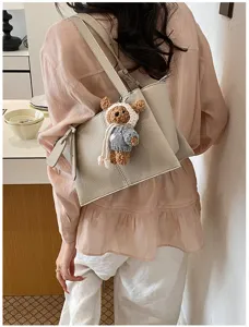Detail view of the elegant leather tote shoulder bag in grey, styled with a cute knitted bear charm.