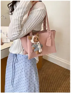 Stylish pink tote bag with cute bear pendant, large capacity shoulder bag for daily commute.