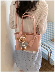 Detailed view of the stylish pink shoulder tote bag with a cute knit bear pendant accessory.