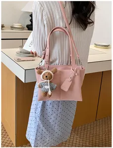 Pink leather tote bag detail view, showing soft material, plush bear charm and handle.