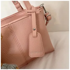 Close-up detail of a pink leather tote handbag featuring textured finish and branded tag.