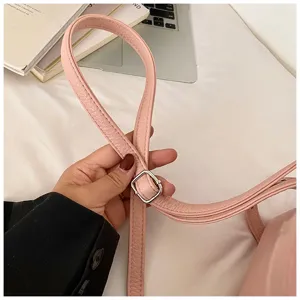 Pink leather crossbody bag strap detail, adjustable metal buckle, high quality fashion accessory.