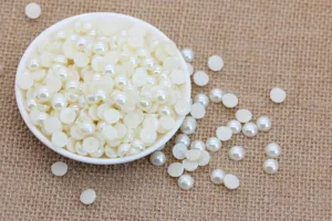 Close-up of white flatback pearls in a small bowl, perfect for DIY phone case decor and crafts.