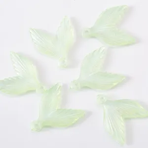 Detailed close-up of light green acrylic mermaid tail charms with glitter finish for DIY jewelry.