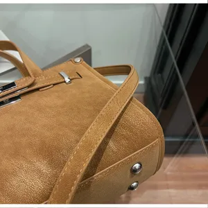 Detail shot of a chic brown suede texture shoulder bag with metal feet and classic hardware.
