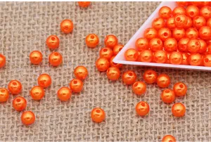 Close-up detail of vibrant orange ABS plastic imitation pearl loose beads for DIY crafts.