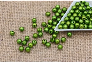 Close-up detail shot of green ABS plastic imitation pearl beads scattered on burlap fabric.