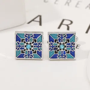 Detailopname van vierkante blauwe emaille manchetknopen met geometrische patronen.
