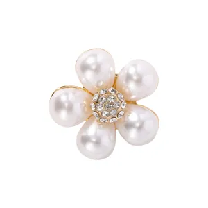 Detalle de elegante broche de flor de perla con centro de estrás brillante y acabado dorado.
