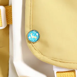Detailed shot of yellow and white backpack with cute deer pattern glass cabochon badge accessory.