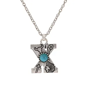 Close-up of the letter X pendant necklace with turquoise stone and bohemian vintage style.