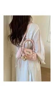 Trendy pink bowling shoulder bag with rivets and cute bear pendant for women daily commute.