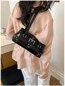 Detalle de bolso de charol negro bajo el brazo con hebilla de metal y tachuelas plateadas chic.