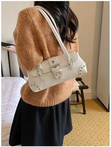 Bolso de hombro blanco en charol con hebilla metálica y detalles de tachuelas punk.