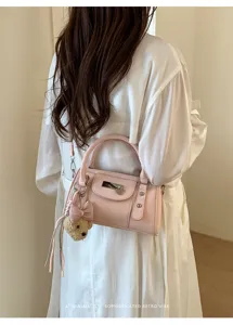 Detailed shot of pink leather pillow bag with cute bow bear pendant and metal lock.