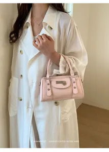 Detail shot of pink bowling handbag featuring metallic clasp and chic rivet accents.