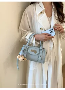 Chic light blue bowling pillow bag with rivet details and cute plush bear charm for women.